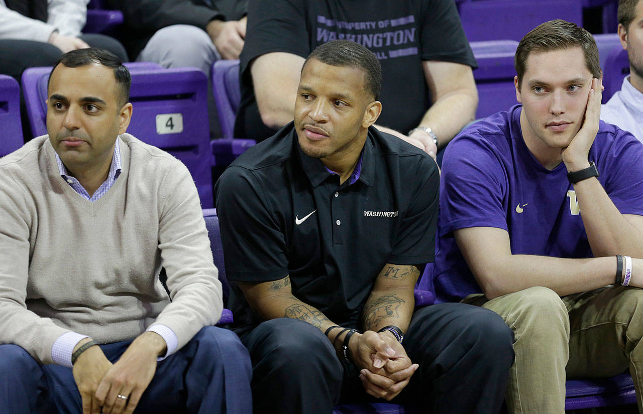 Will Conroy (center) listens as Mike Hopkins is introduced as Washington’s new head men’s basketball coach on March 22, 2017 in Seattle. Conroy is the lone holdover from former coach Lorenzo Romar’s staff. (AP Photo/Ted S. Warren)