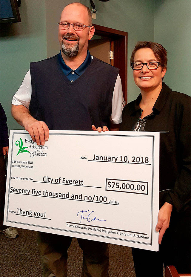 Evergreen Arboretum and Gardens President Trevor Cameron on Jan. 10 presents Everett Mayor Cassie Franklin with a check for $75,000 to finish the South Area of the arboretum. (Contributed photo)