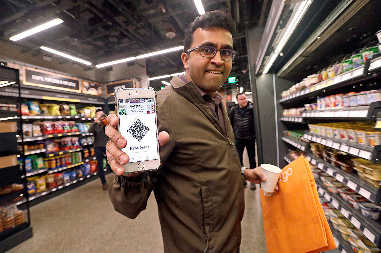 Amazon employee Krishna Iyer shows off an Amazon Go app as he shops in the store on Monday in Seattle. (AP Photo/Elaine Thompson)