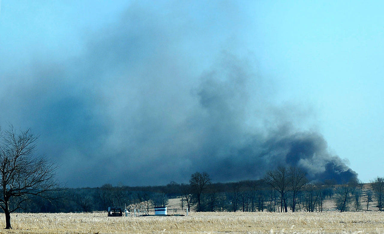 Smoke billows from the site of a gas well fire near Quinton, Okla., early Monday, Jan. 22, 2018. Several people were missing after a fiery explosion ripped through the eastern Oklahoma drilling rig, sending plumes of black smoke into the air and leaving a derrick crumpled onto the ground, an emergency official said. (Kevin Harvison / The McAlester News-Capital via AP)
