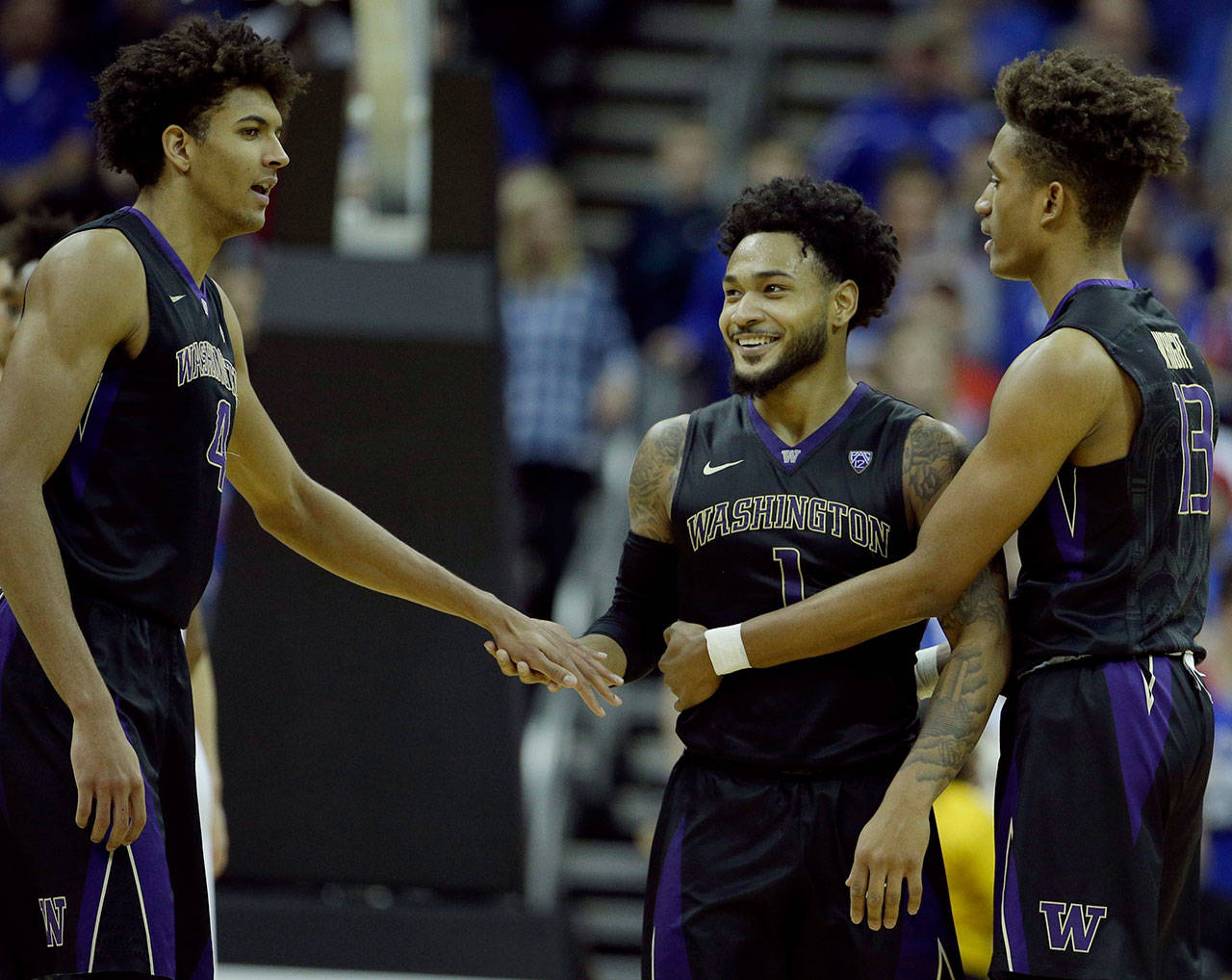 Washington’s David Crisp (center) Matisse Thybulle (left) and Hameir Wright celebrate a basket during a game against Kansas on Dec. 6, 2017 in Kansas City, Missouri. Washington won 74-65. (AP Photo/Charlie Riedel)