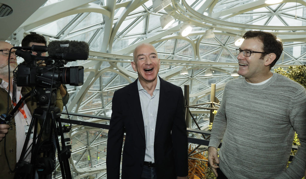 CEO and founder of Amazon.com Jeff Bezos (center) laughs as he talks with Ron Gagliardo (right), the lead horticulturist of the Amazon Spheres, following the grand opening ceremony Monday in Seattle. (AP Photo/Ted S. Warren)
