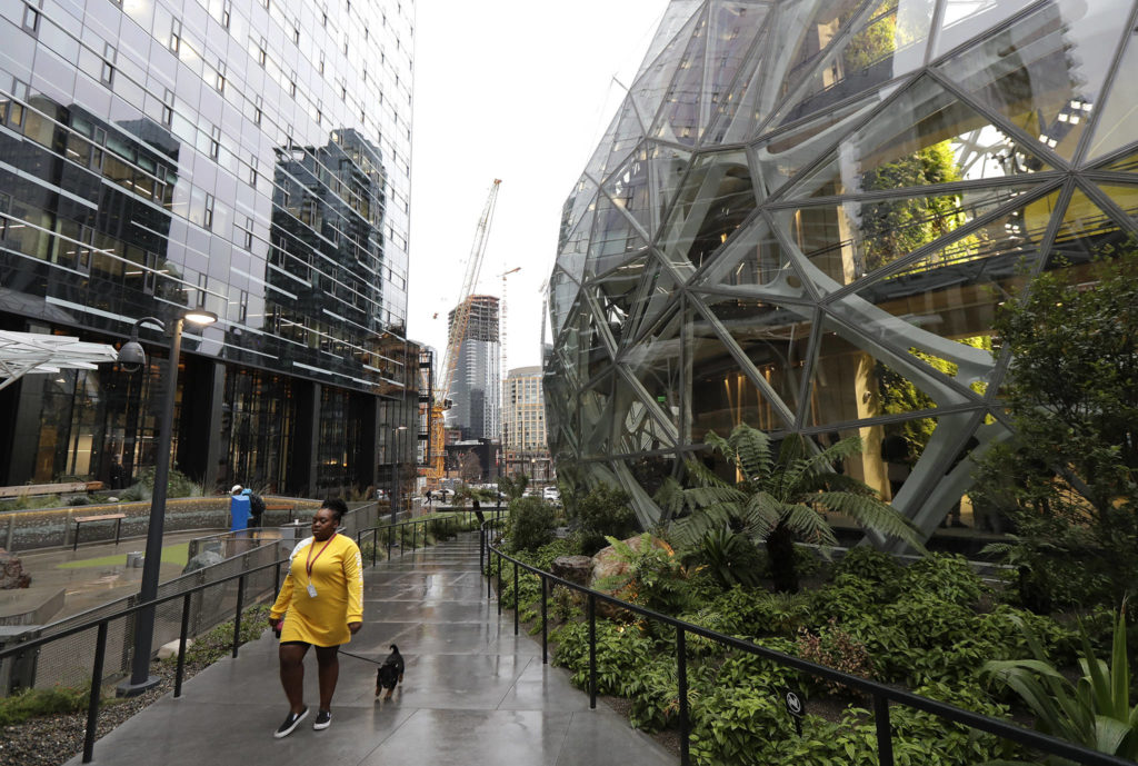 A worker walks her dog past the Amazon Spheres in downtown Seattle on the day of the grand opening of the geodesic domes. (AP Photo/Ted S. Warren)
