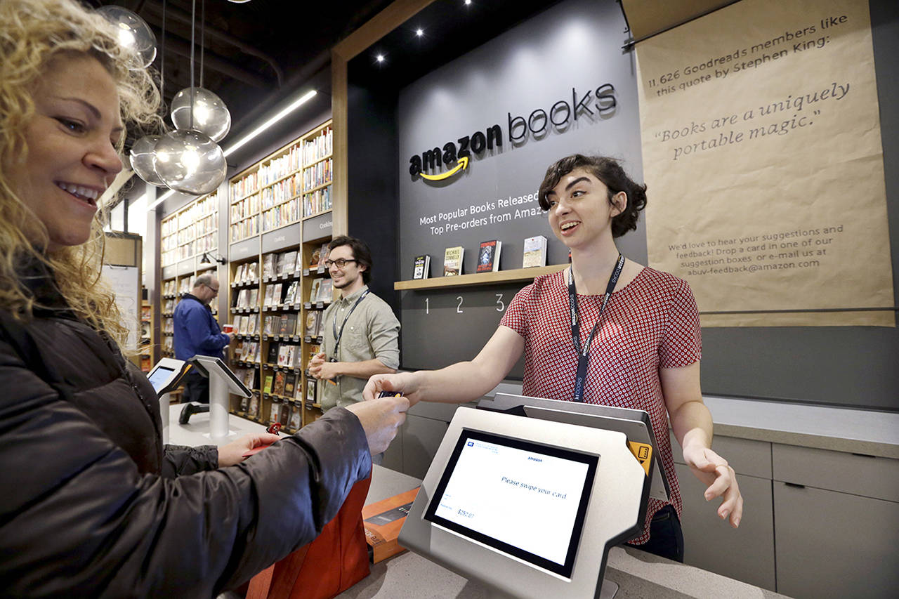Customer Kirsty Carey (left) gets ready to swipe her credit card for clerk Marissa Pacchiarotti at Amazon Books in Seattle in 2015. (AP Photo/Elaine Thompson, File)