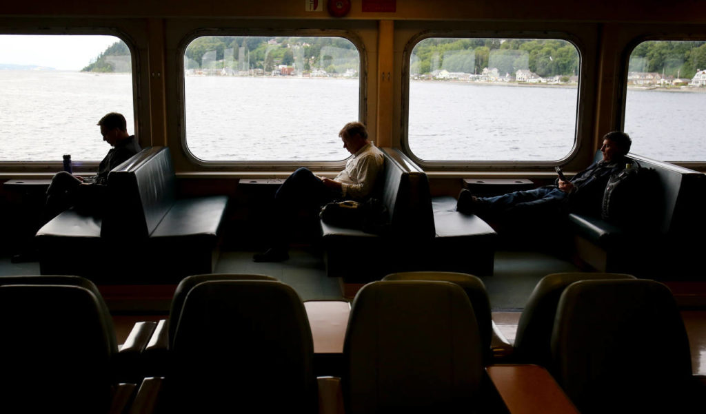 Morning commuters relax in booths aboard a ferry making its way from Clinton to Mukilteo. (Kevin Clark / The Herald)
