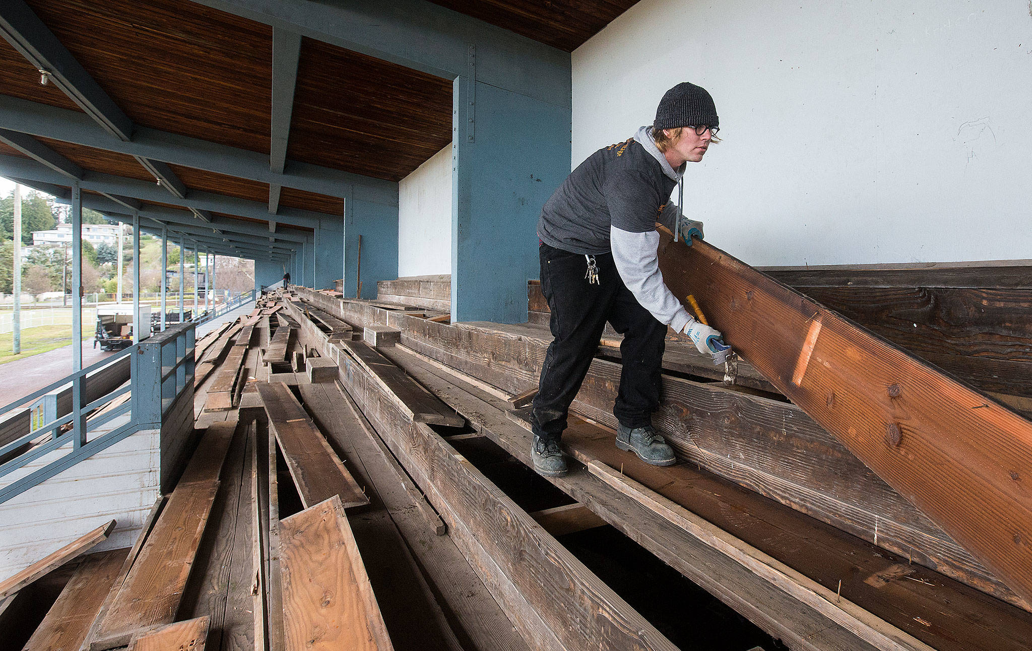 Worker James Ford, of Ballard Reuse, pulls up bleacher boards at the former Edmonds High School stadium at Civic Field on Tuesday in Edmonds. The removal makes way for development of a park at the eight-acre site. (Andy Bronson / The Herald)