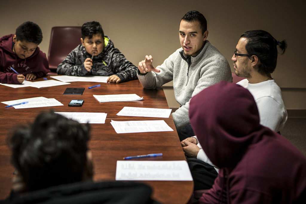 Casino Road YMCA Youth Outreach Director Ricardo Heredia (center right) and mentor Irvin Enriquez (right) lead an evening discussion about rap lyrics and gangs with kids at the community center on East Casino Road in Everett on Jan. 11. (Ian Terry / The Herald)
