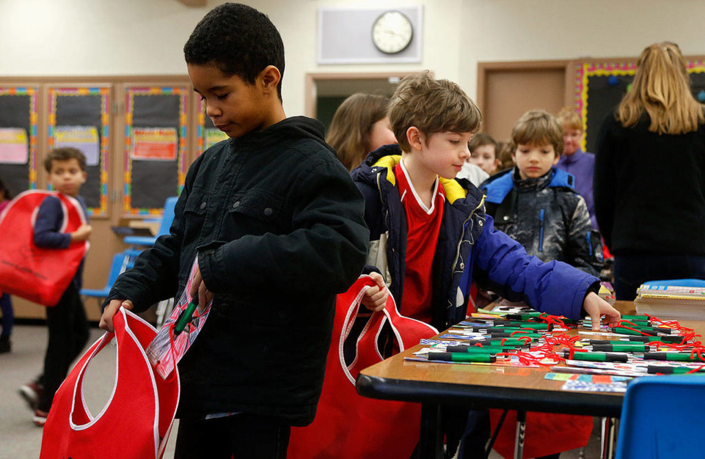 Emerson Elementary School third-graders Gavin Walcott (nearest) and Curtis Walker (near right) place gifts in Buddy Bags that they will give to people living in a local nursing home. (Dan Bates / The Herald)
