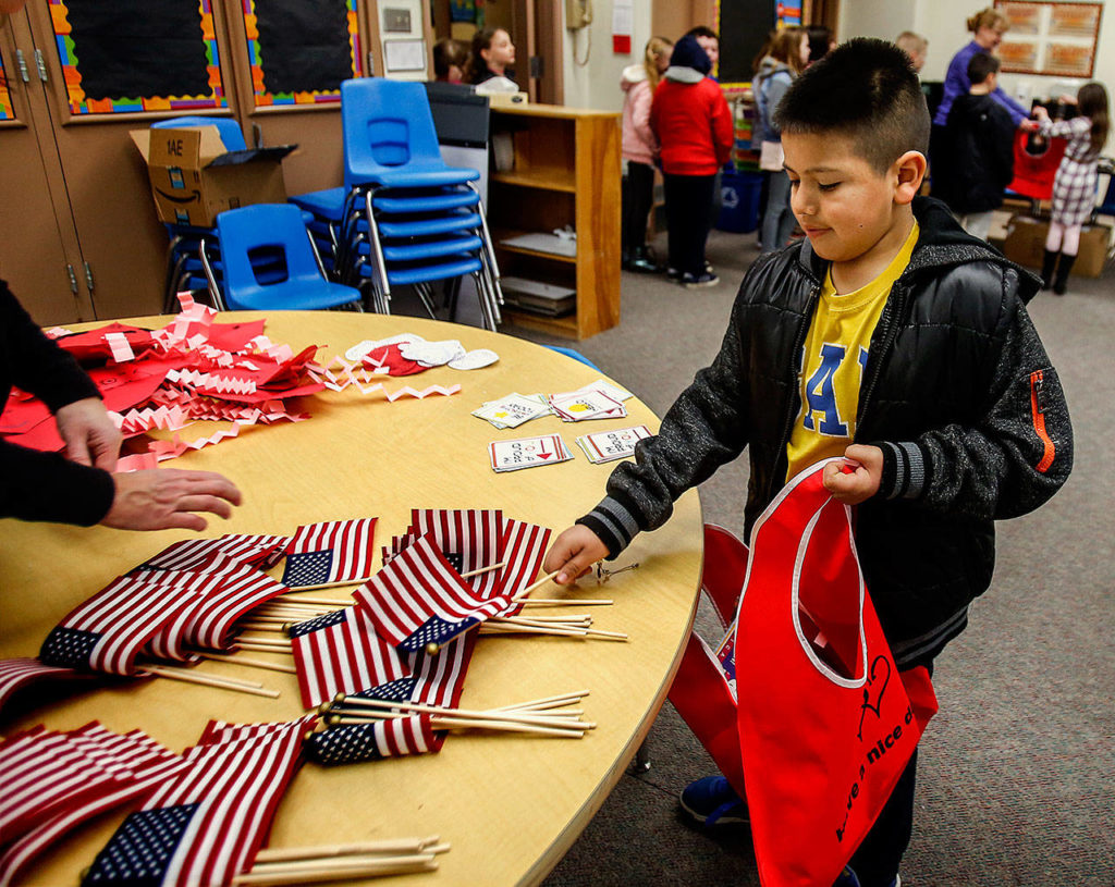 Emerson Elementary School third-grader Eder Lara, 9, picks out a small American flag and places it in a Buddy Bag as a gift to someone in a local nursing home. (Dan Bates / The Herald)
