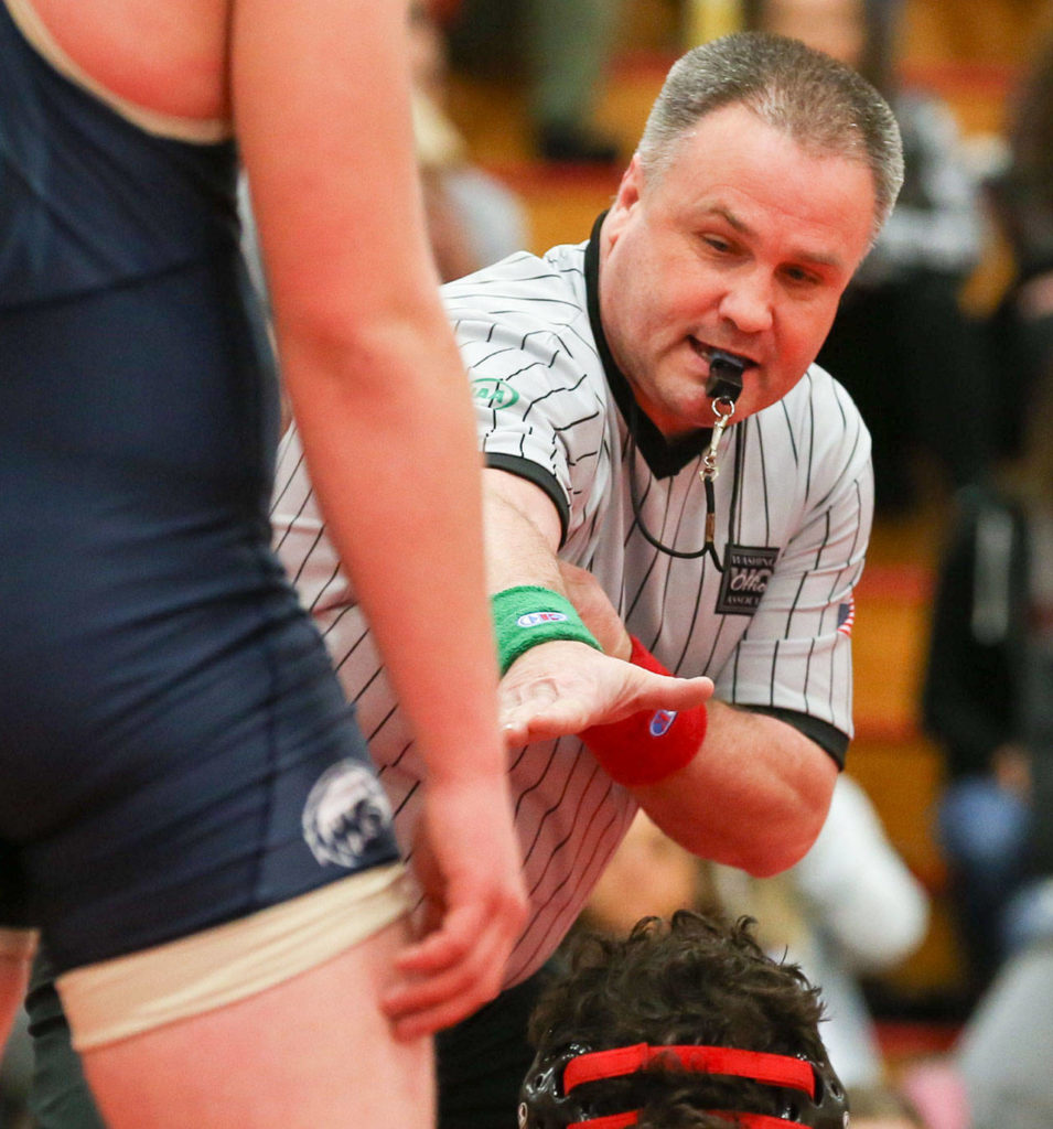 Match official Al Rivers signals for Arlington’s Connor Stockman (standing) to cover Marysville Pilchuck’s Ikaika Nawelhi during a Wesco 3A North dual on Jan. 25 in Marysville. (Kevin Clark / The Daily Herald)
