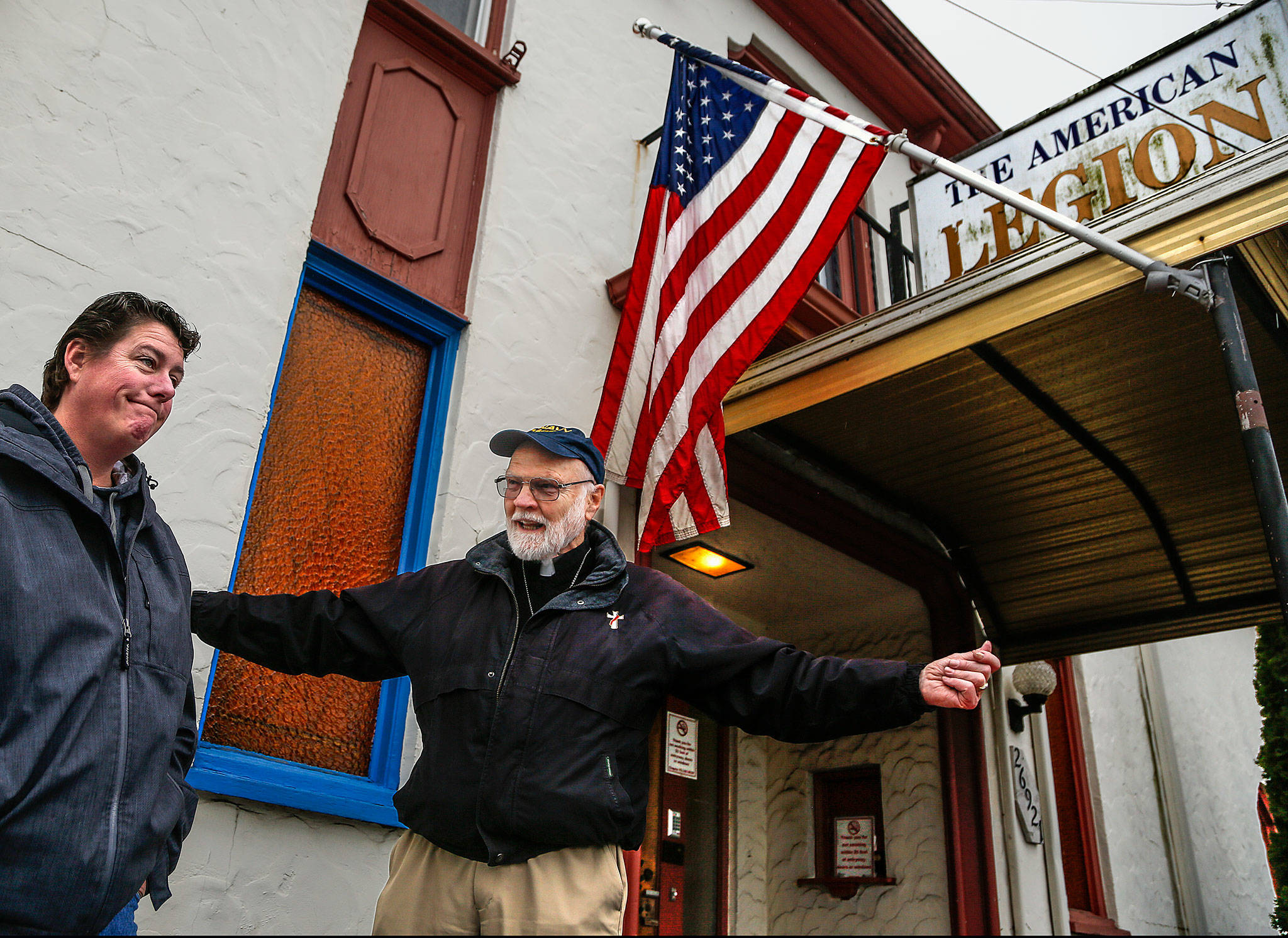 Just outside Stanwood’s American Legion Post 92 Thursday, Navy veteran and Post Chaplain Phil Lewis, 85, talks about major work needed on the building, which is only a few years younger than he is. Post Cmdr. Gina Seegert might appear to be suffering from a little sticker shock, considering they need to raise $90,000. (Dan Bates / The Herald)