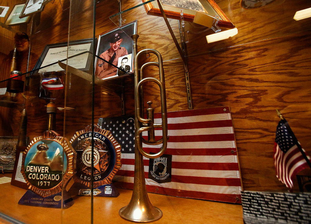 What appears to be a vintage military bugle stands near the front of a large display case at Stanwood American Legion Post 92 that provides a close-up look at numerous items dating back to World War I. (Dan Bates / The Herald)
