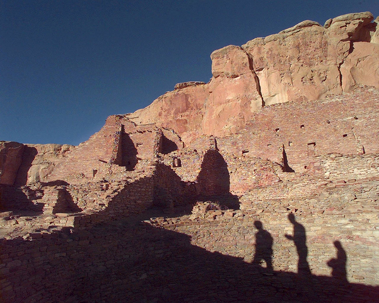 Tourists cast their shadows on the ancient Anasazi ruins of Chaco Canyon in New Mexico. Dozens of protests have been filed by tribal officials, environmentalists and others as federal land managers consider leasing parcels in northwestern New Mexico for oil and gas development that critics say are too close to sites they consider culturally significant. (AP Photo/Eric Draper, File)