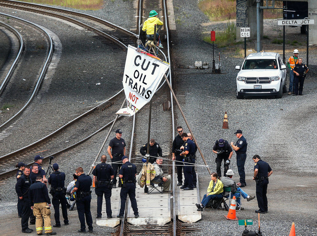 Protesting oil and coal shipments in the BNSF Railway yard in the Delta area of north Everett on Sept. 2, 2014, the “Delta 5” attached themselves to a large metal tripod and were subsequently arrested by Everett police. The five were Patrick Mazza (center), Abby Brockway (on top), Mike Lapointe (left), and Liz Spoerri, tied to pole back-to-back with Jackie Minchew (far right). (Dan Bates / The Herald)
