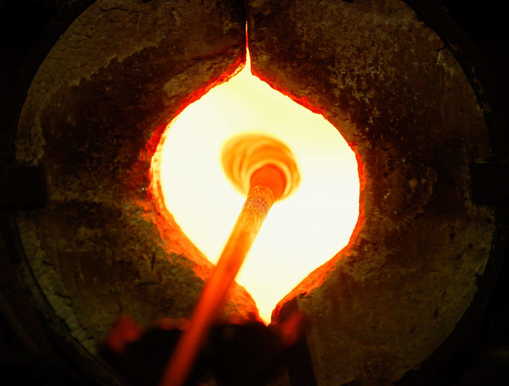 Ellinger super-heats a glob of glass in a 2,300-degree furnace at Glass Quest Studio. (Dan Bates / The Herald)

