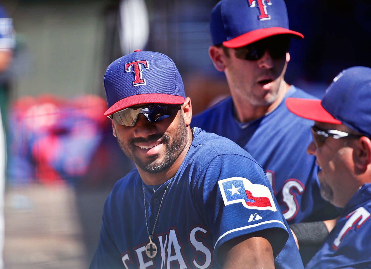 Seahawks quarterback Russell Wilson talks with fellow Texas Rangers in the dugout during a spring training game in 2015. Wilson was traded from the Rangers to the Yankees on Wednesday. (AP Photo/Lenny Ignelzi)