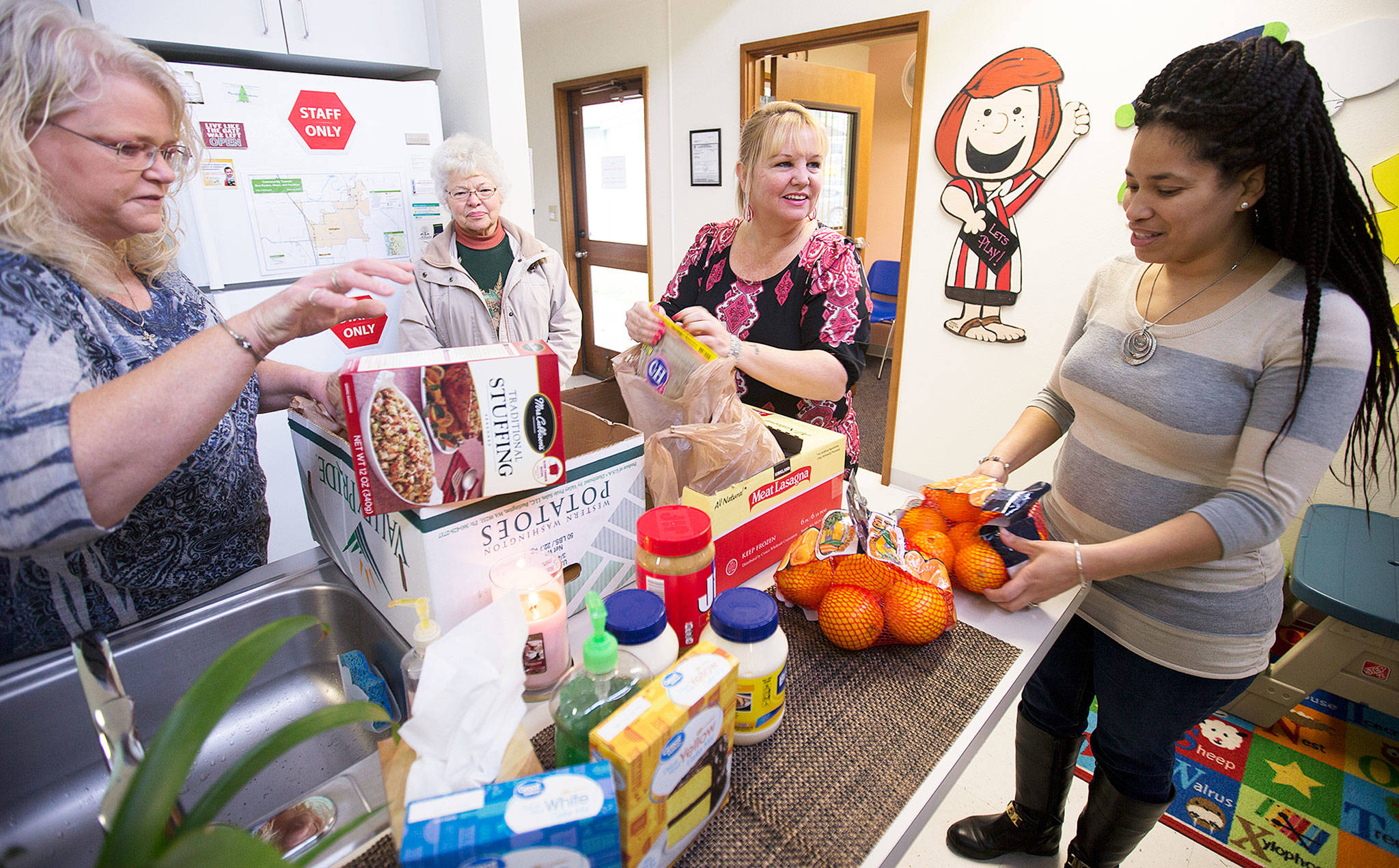 Peggy Ray (center) and others organize food at the Arlington Community Resource Center last Nov. 20. Ray, a manager with Lutheran Community Services, is one of dozens of people in Snohomish County who have been involved in bringing trauma education to service providers. (Andy Bronson / The Herald)