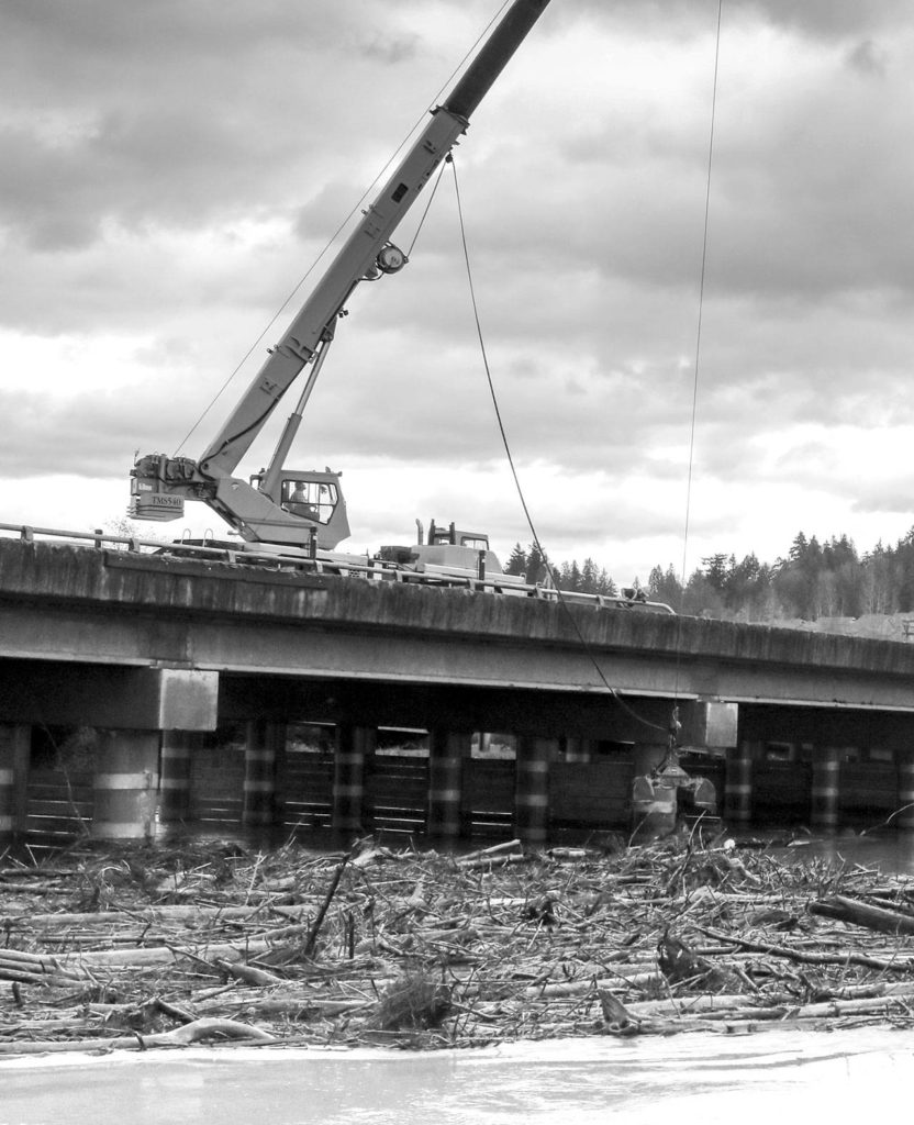 Crews of the Department of Transportation work to clear a log jam on the Ebey Slough at the trestle bridge Wednesday afternoon in Everett on November 22, 2017. (Kevin Clark / The Herald)
