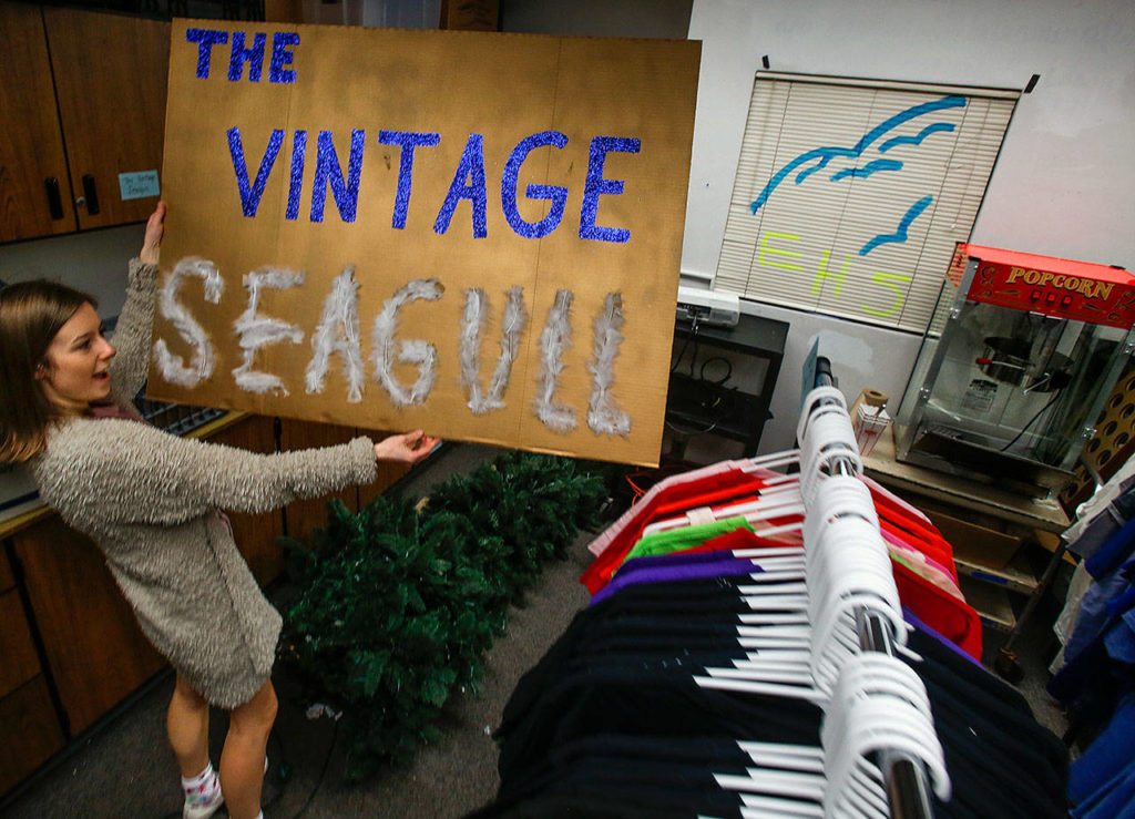 In a small storage room at Everett High School, senior Danielle Scanes looks for a spot to hang a new sign. She is starting a thrift shop at school with plans to sell donated, recycled blue and gold spirit gear—nothing priced over $5—to give all kids a chance to show their school colors. (Dan Bates / The Herald)
