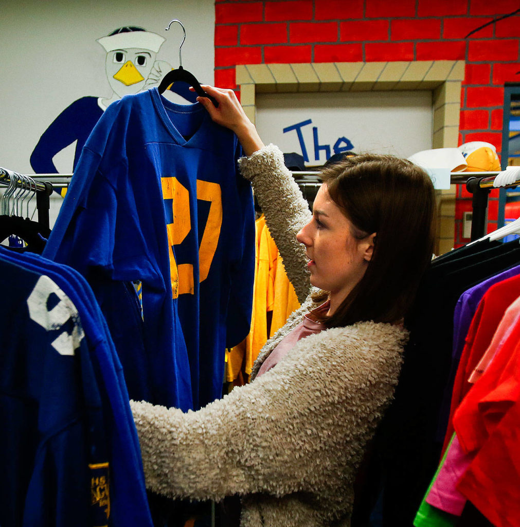 In a small storage room at Everett High School, senior Danielle Scanes hangs some nice used jerseys and straightens the racks in what will soon be a new thrift shop at the school. She plans to sell donated, recycled blue and gold spirit gear—nothing priced over $5—to give all kids a chance to show their school colors. (Dan Bates / The Herald)
