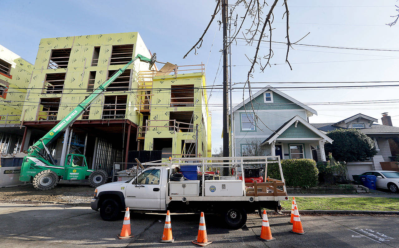 A four-story mixed-use building is under construction adjacent to an older, single-family home in Seattle. (AP Photo/Elaine Thompson)
