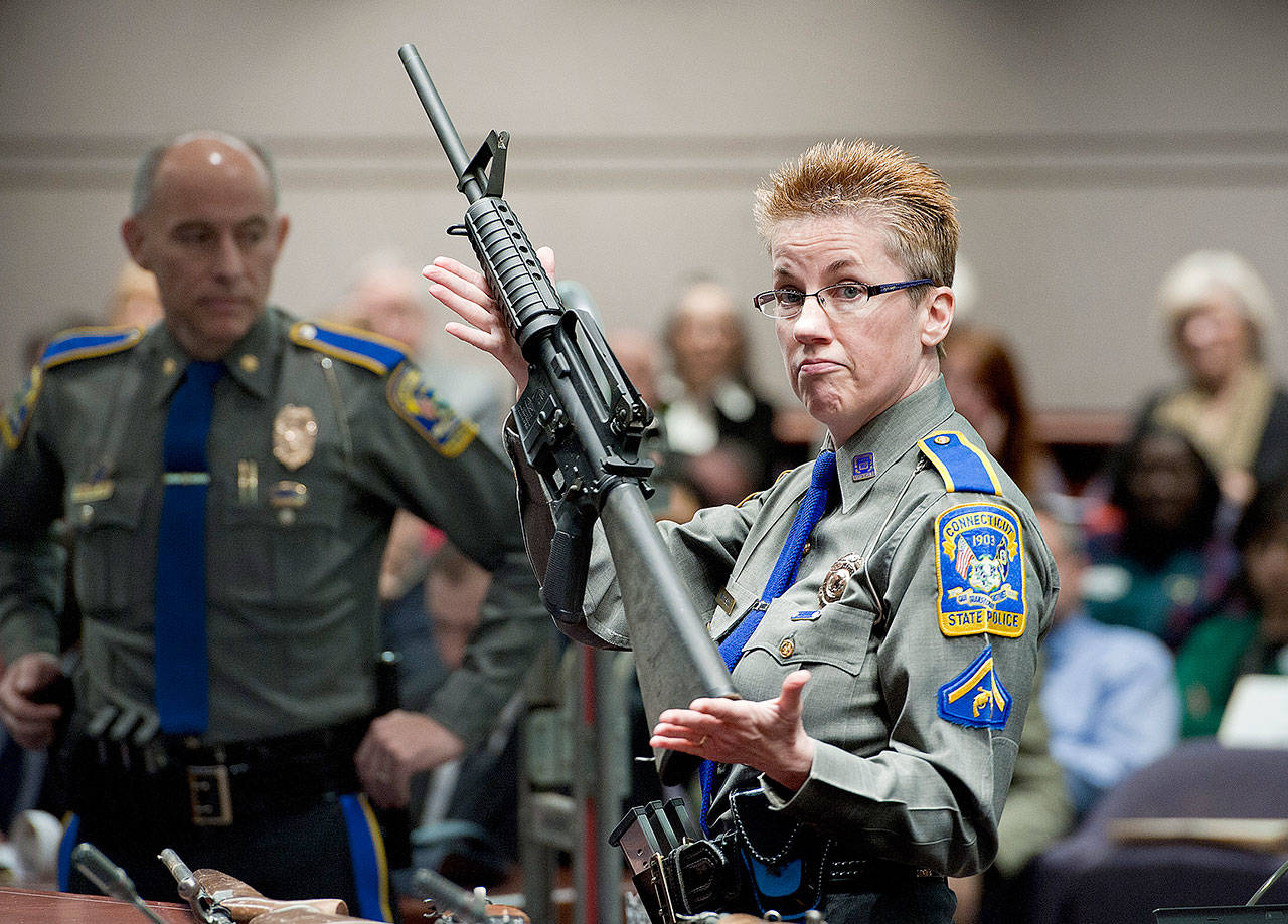 Firearms training unit Detective Barbara J. Mattson, of the Connecticut State Police, holds up a Bushmaster AR-15 rifle, the same make and model of gun used by Adam Lanza in the Sandy Hook School shooting, during a hearing of a legislative subcommittee in Hartford, Connecticut, on January 23, 2013. (AP Photo/Jessica Hill, File)