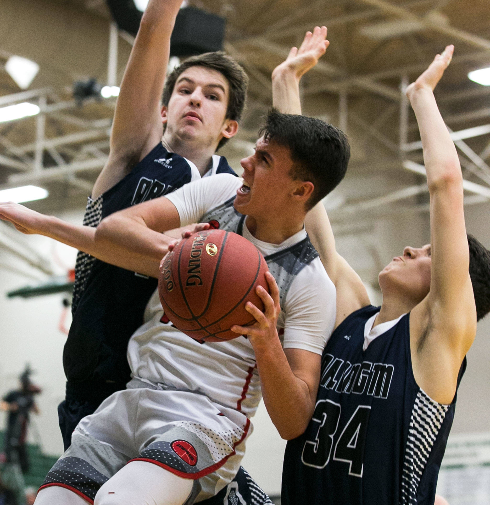 Marysville Pilchuck’s Josiah Gould attempts a shot with Arlington’s Max Smith (left) and Josh Gutierrez defending during a district playoff game on Feb. 14, 2018, at Jackson High School in Mill Creek. (Kevin Clark / The Herald)
