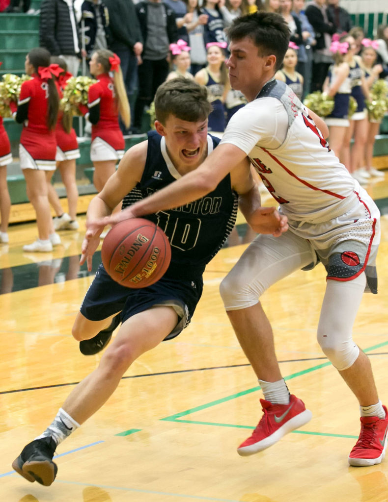 Marysville Pilchuck’s Josiah Gould reaches across and fouls Arlington’s Anthony Whitis during a district playoff game on Feb. 14, 2018, at Jackson High School in Mill Creek. (Kevin Clark / The Herald)

