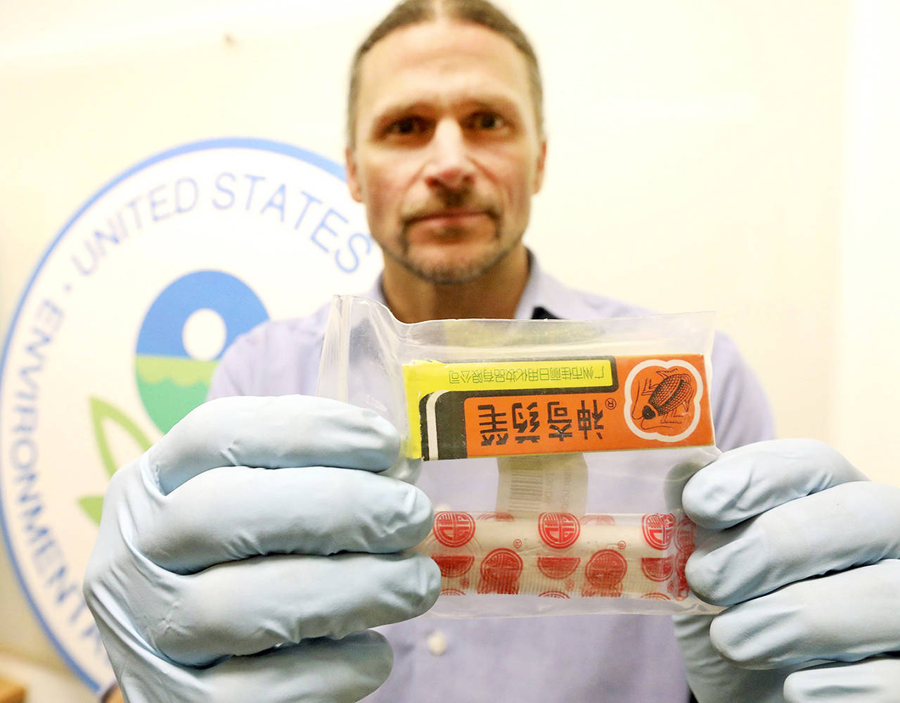 Environmental Protection Agency enforcement officer Chad Schulze displays one of the banned pesticides that investigators say was listed for sale on Amazon. (Greg Gilbert/The Seattle Times via AP)