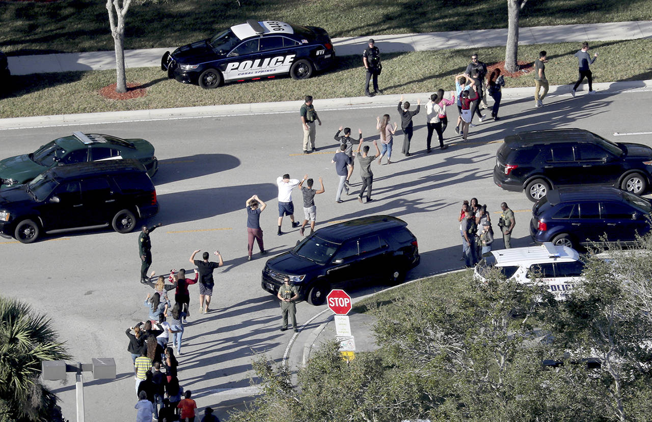 Students hold their hands in the air as they are evacuated by police from Marjory Stoneman Douglas High School in Parkland, Florida, after a shooter opened fire on the campus Feb. 14. (Mike Stocker/South Florida Sun-Sentinel via AP, File)