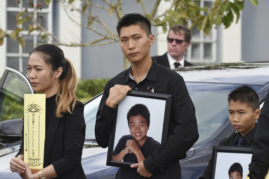 Jason Wang (center) holds a picture of his brother Peter, along with his younger brother, Alex, after his brother’s funeral at Kraeer Funeral Home in Coral Springs, Florida. (Taimy Alvarez/South Florida Sun-Sentinel via AP)
