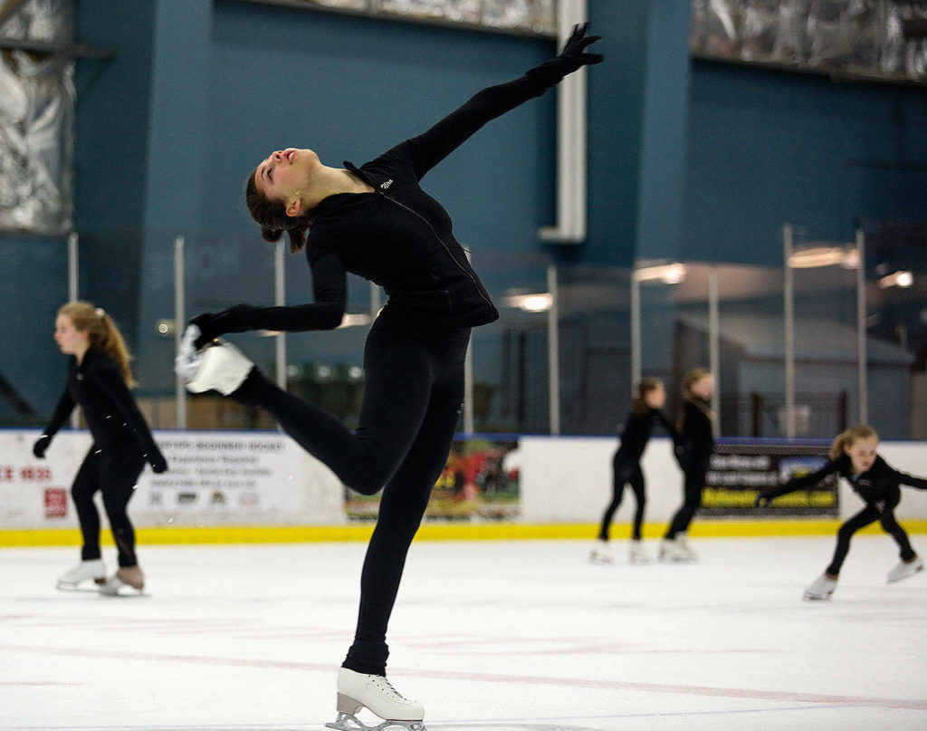 Nira Barlow, 16, grabs her skate in a move while practicing Thursday at Everett’s Community Ice Rink. (Dan Bates / The Herald)
