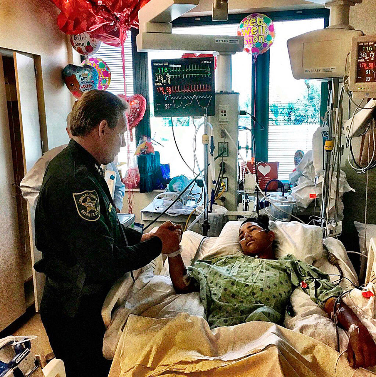 Broward County Sheriff Scott Israel holds the hand of Anthony Borges, 15, a student at Marjory Stoneman Douglas High School on Sunday. Borges is credited with saving the lives of at least 20 other students. (Broward County Sheriff’s Office via AP)