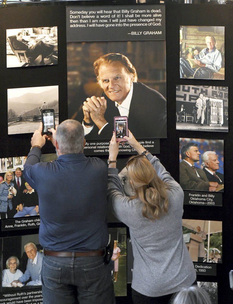 Chuck and Angela Riddle, of Morganton, North Carolina, photograph a memorial display in tribute to Rev. Billy Graham inside the chapel at the Billy Graham Training Center at the Cove on Wednesday in Asheville, North Carolina. The couple came to pay their respects and said Graham was a big influence in their lives. (AP Photo/Kathy Kmonicek)
