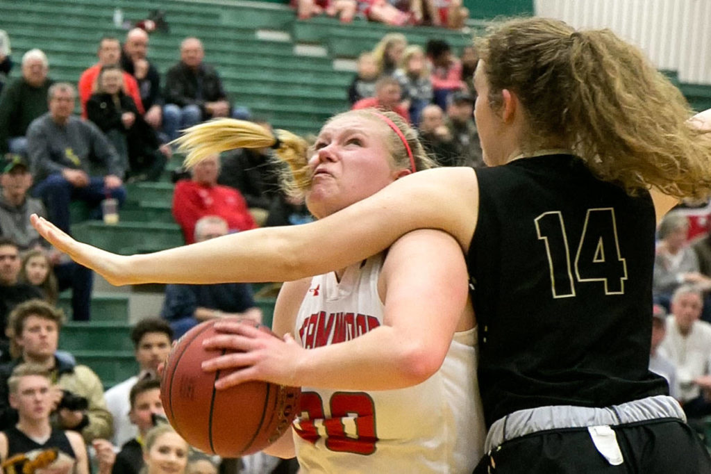Stanwood’s Kaitlin Larson is fouled by Lynnwood’s Liz Jones during a regional playoff game on Feb. 24, 2018, at Jackson High School in Mill Creek. (Kevin Clark / The Herald)
