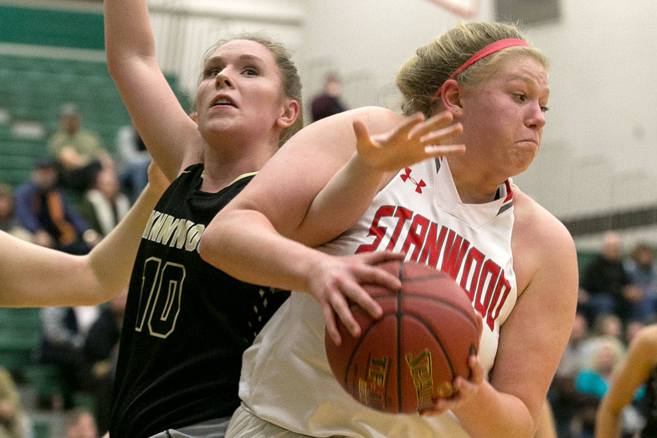 Stanwood’s Kaitlin Larson gathers a rebound with Lynnwood’s Abby Douglas tangled Saturday afternoon at Jackson High School in Mill Creek on February 24, 2018. (Kevin Clark / The Daily Herald)