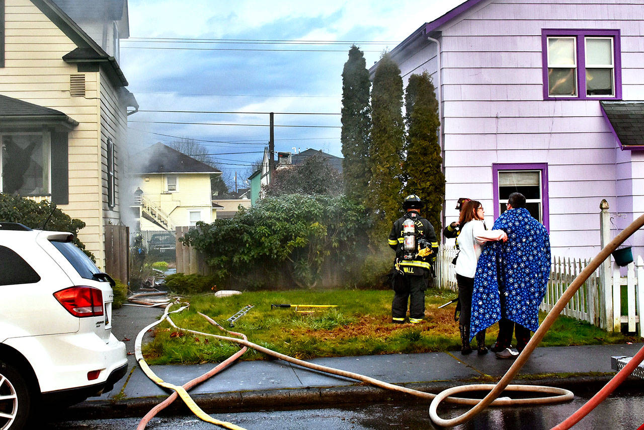 Jain McCaughan, 60, a nurse, comforts a man who escaped a house fire Saturday evening in Everett. (Caleb Hutton / The Herald)