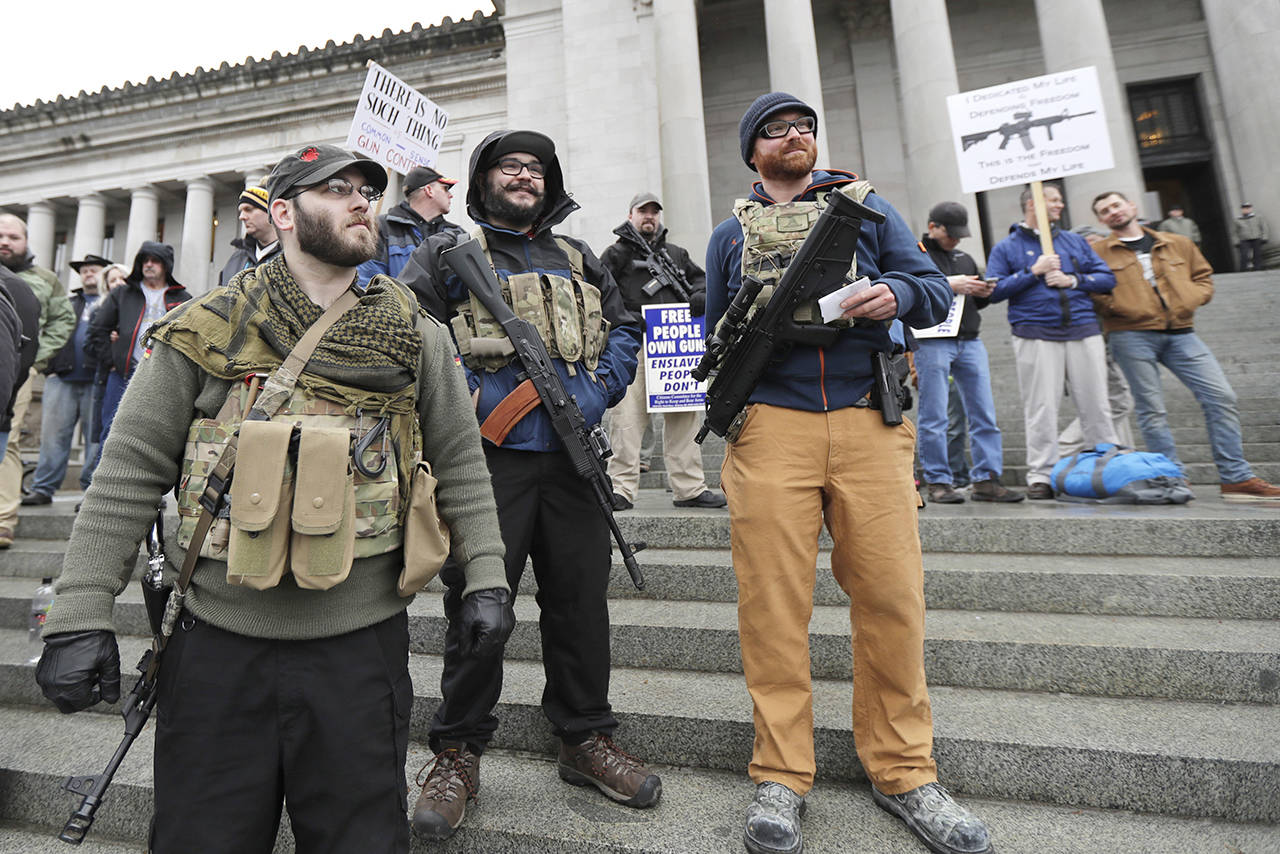 Ian Stobie (left), Jake Garza (second from left) and Ben Garrison, all of Puyallup, open-carry their guns on the steps of the Legislative Building as they attend a gun rights rally Jan. 12 at the Capitol in Olympia. (Ted S. Warren / Associated Press file)