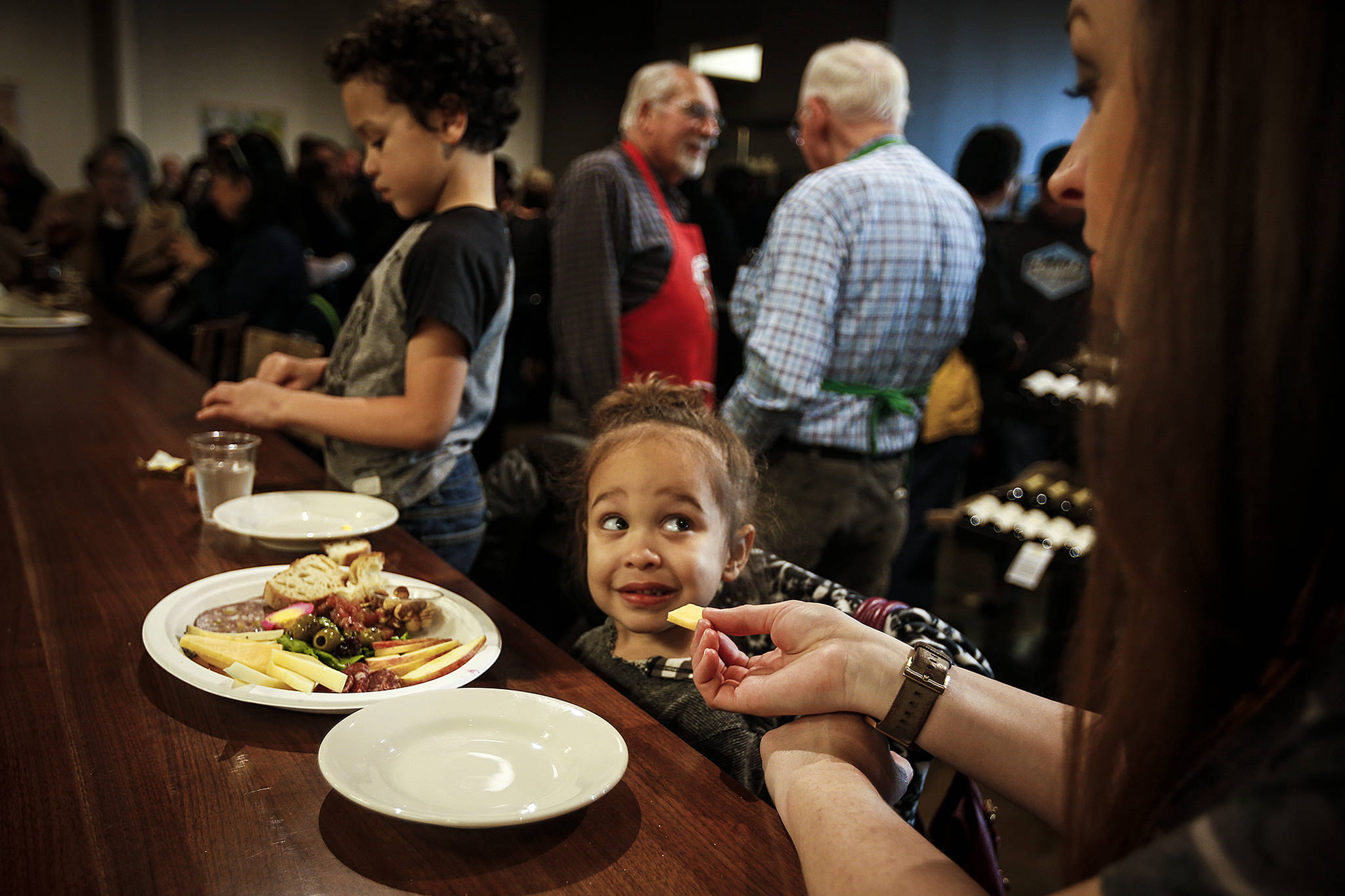 Alivia Broady, 3, gives her mom, Shauna, a look after being offered a piece of artisanal cheese along with her brother, Bronson, 6, during Farms Market’s grand opening celebration in Everett on Thursday. Located on Grand Avenue in downtown Everett, Farms Market will be a year-round market offering goods from local farmers. (Ian Terry / The Herald)