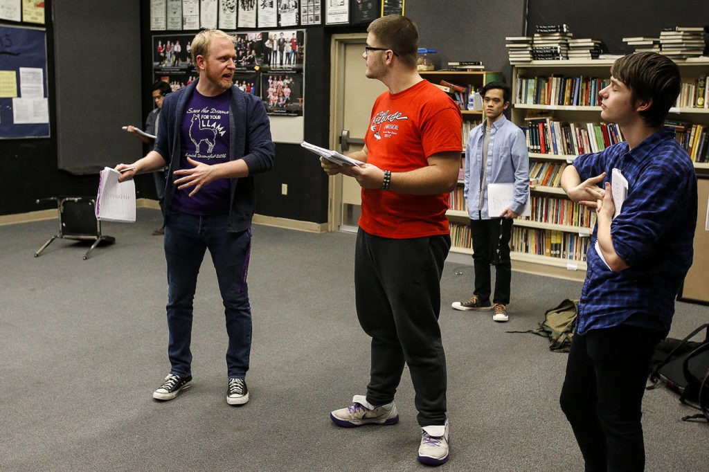 Kamiak High School drama teacher Bryan Sullivan (left) helps students Jack Burrows (center), Eddie Kouthong (center right) and Martin Albrecht (right) with lines during a “Spamalot” rehearsal on Thursday. (Ian Terry / The Herald)

