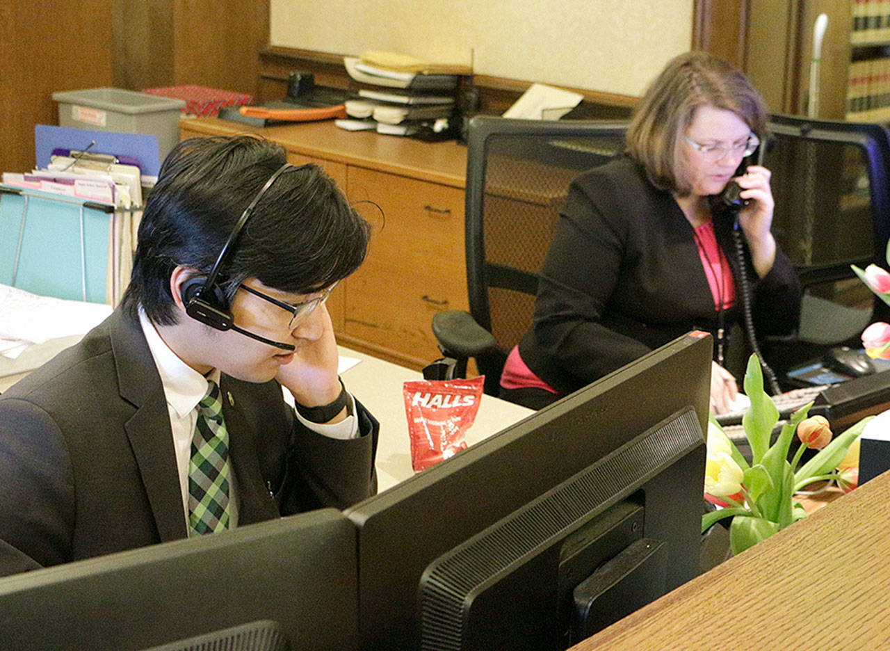 Kento Azegami (left) and Jeanne Blackburn answer phones at the front desk at Gov. Jay Inslee’s office in Olympia on Thursday. Inslee’s office has been receiving thousands of emails and phone calls asking him to veto a bill passed hastily by the Legislature last week that would circumvent a recent court ruling that found state lawmakers are fully subject to the state’s Public Records Act. (AP Photo/Rachel La Corte)