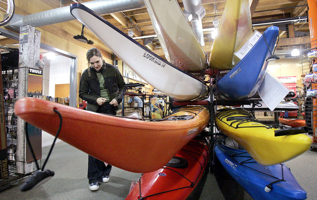 In 2006 photo, a woman looks over sea kayaks as she shops at an REI store in Seattle. Outdoor retailer REI said Thursday that it’s halting future orders of some popular brands whose parent company also makes ammunition and assault-style rifles. (AP Photo/Elaine Thompson, File)