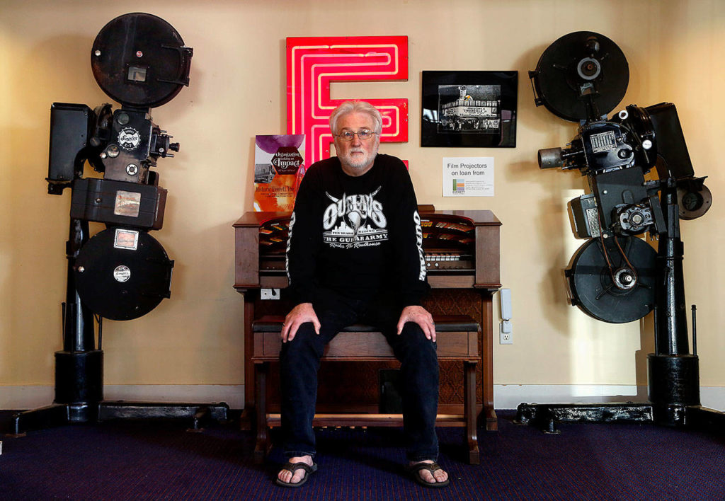 The Historic Everett Theatre is for sale, with an asking price of $2,450,000. Since 2014, brothers Craig and Curt Shriner have brought crowds to downtown Everett between music acts and films. Here, Curt Shriner sits at an organ between two vintage movie projectors in the lobby. (Dan Bates / The Herald)
