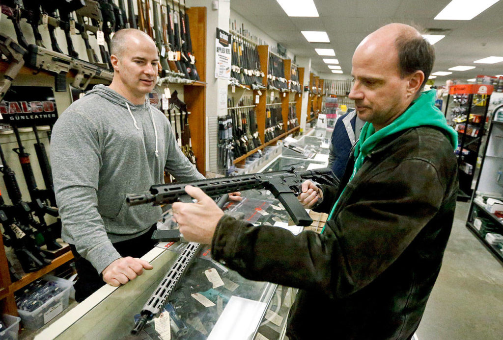 Wes Morosky, owner of Duke’s Sport Shop in New Castle, Pennsylvania, helps Ron Detka as he shops for a rifle Friday. (AP Photo/Keith Srakocic)
