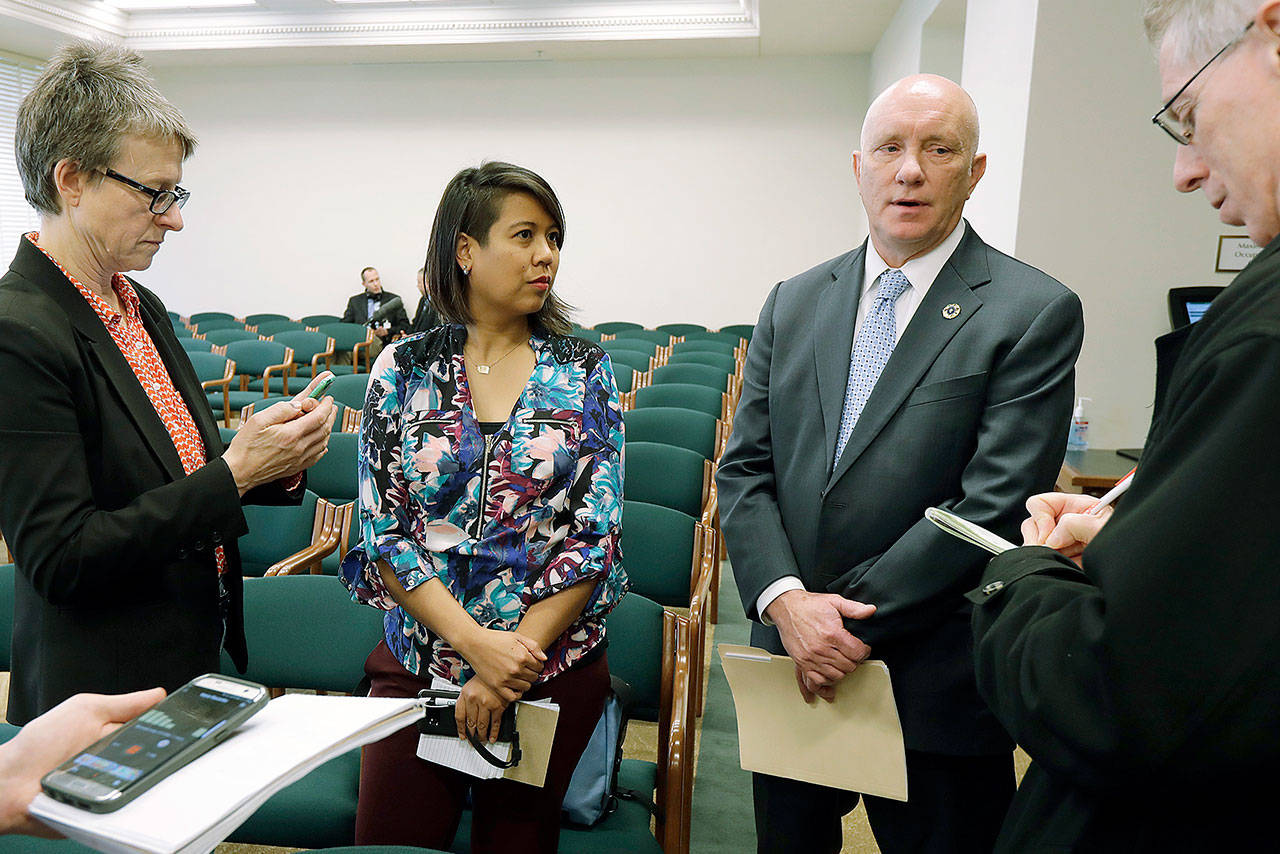 Steven Strachan (third from left), executive director of the Washington Association of Sheriffs and Police Chiefs, talks to reporters along with Leslie Cushman (far left) and Heather Villanueva (second from left), both of De-Escalate Washington, on Tuesday in Olympia after a House hearing on the use of deadly force by law enforcement officers. (Ted S. Warren / Associated Press)