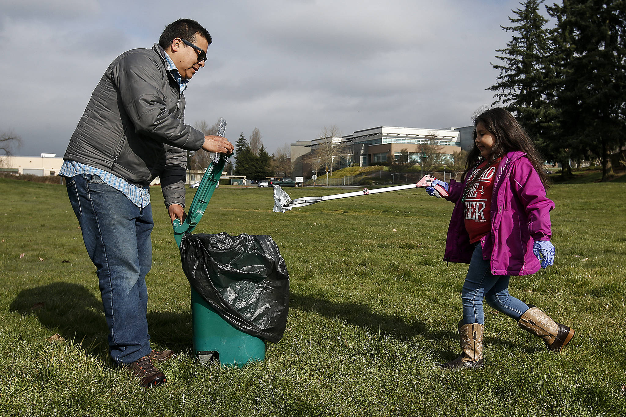 Alberto Acompa and his daughter Mia, 6, clean up trash at Wiggums Hollow Park in Everett on Saturday, March 17. (Ian Terry / The Herald)