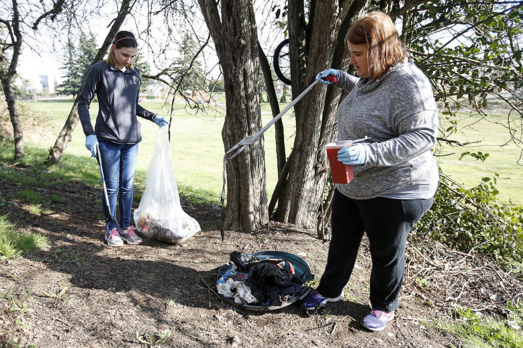 Liz Robinson (right) picks up trash with her daughter, Kesley, during a volunteer cleanup of Wiggums Hollow Park in Everett on Saturday. (Ian Terry / The Herald)
