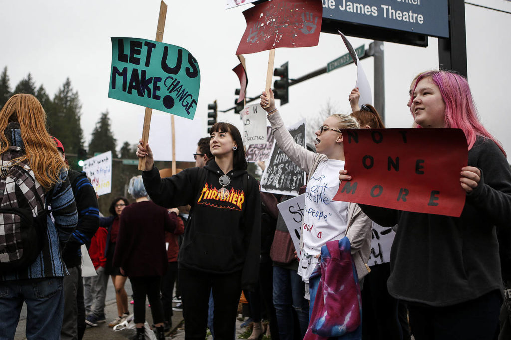 Scriber Lake High School students Kyra Wasbrekke (center), Jasmine Smith (center right) and Vivian Beirwagen (right) stand at the corner of Edmonds Way and 100th Avenue West during a walkout on Wednesday to bring awareness to increasing gun violence in schools. (Ian Terry / The Herald) 
