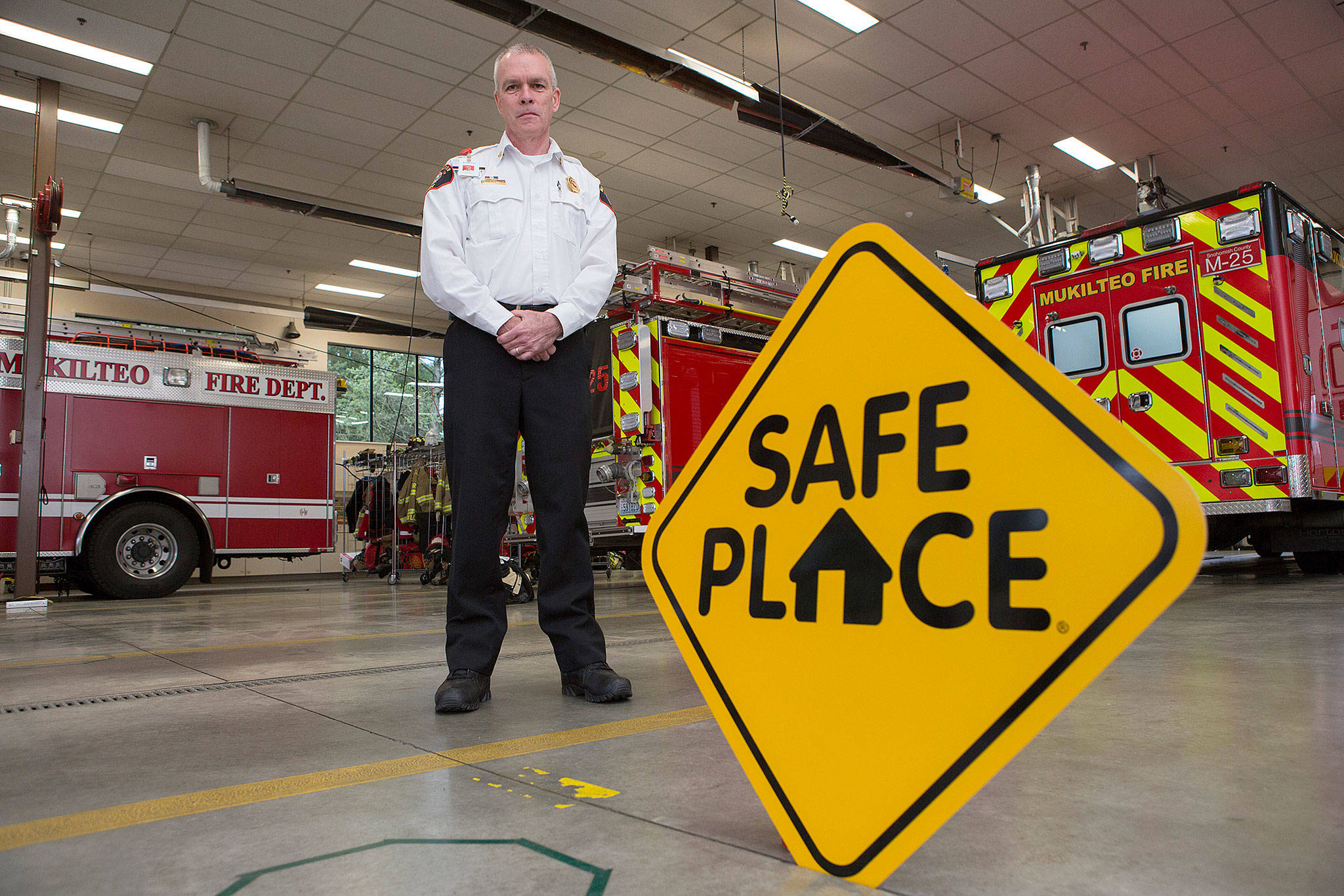 Mukilteo Fire Department Chief Chris Alexander stands near one of the new signs, indicating that the fire station will be a safe place for teens to go when in crisis. (Andy Bronson / The Herald)