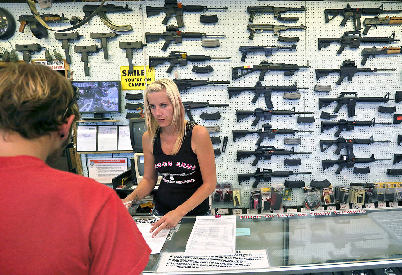 In this 2014 photo, a gun store employee helps a customer at Dragonman’s, east of Colorado Springs, Colorado. (AP Photo/Brennan Linsley, file)